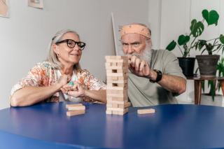 Tangram en bois aux pièces larges posé sur une table, manipulé à pleine main